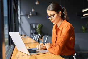 Professional working on a laptop at a desk, focused on digital tasks and data analysis in a modern workspace.