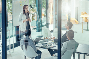 Professional presenting to a small group during a collaborative meeting in a modern office setting